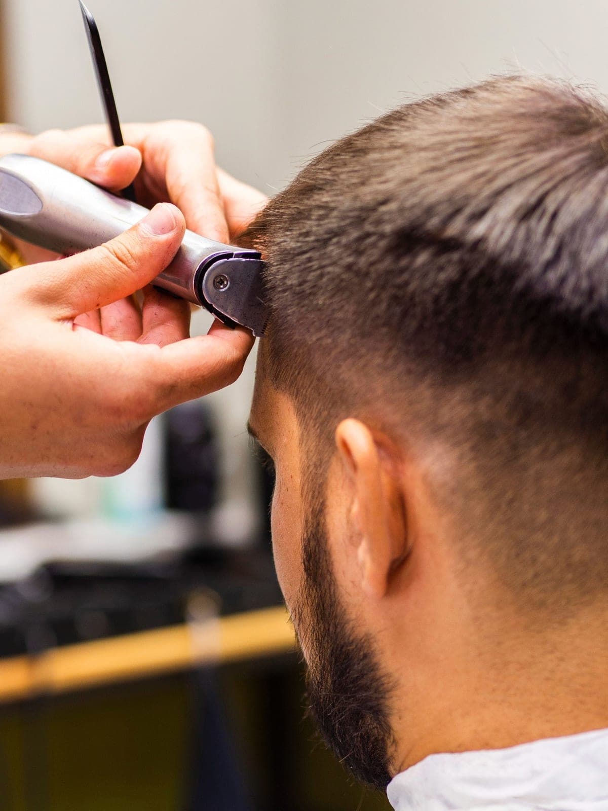 Herrenhaarschnitt: die Konturen am Hinterkopf werden mit der Haarschneidemaschine ausrasiert